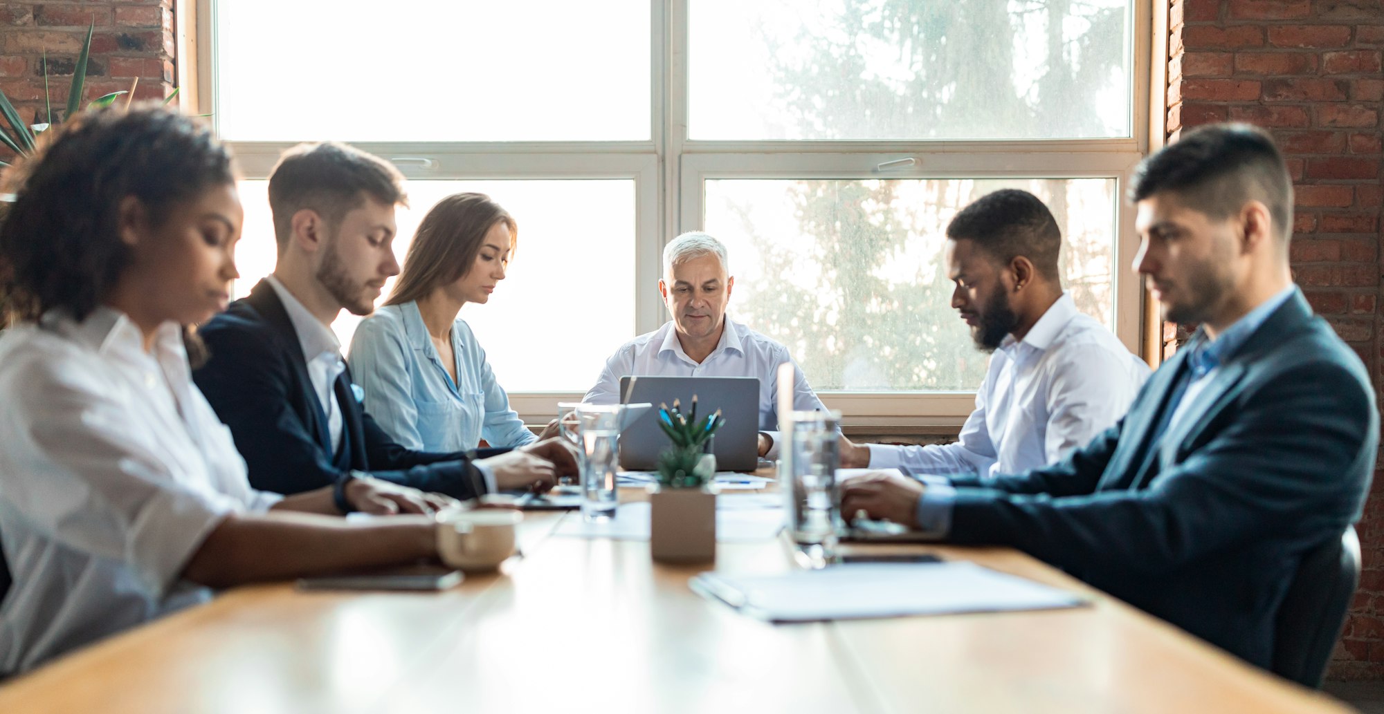 Colleagues Working During Corporate Meeting Sitting At Desk In Office