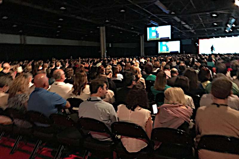 Large Audience crowd gathering at a conference watching the guest speaker on the main stage